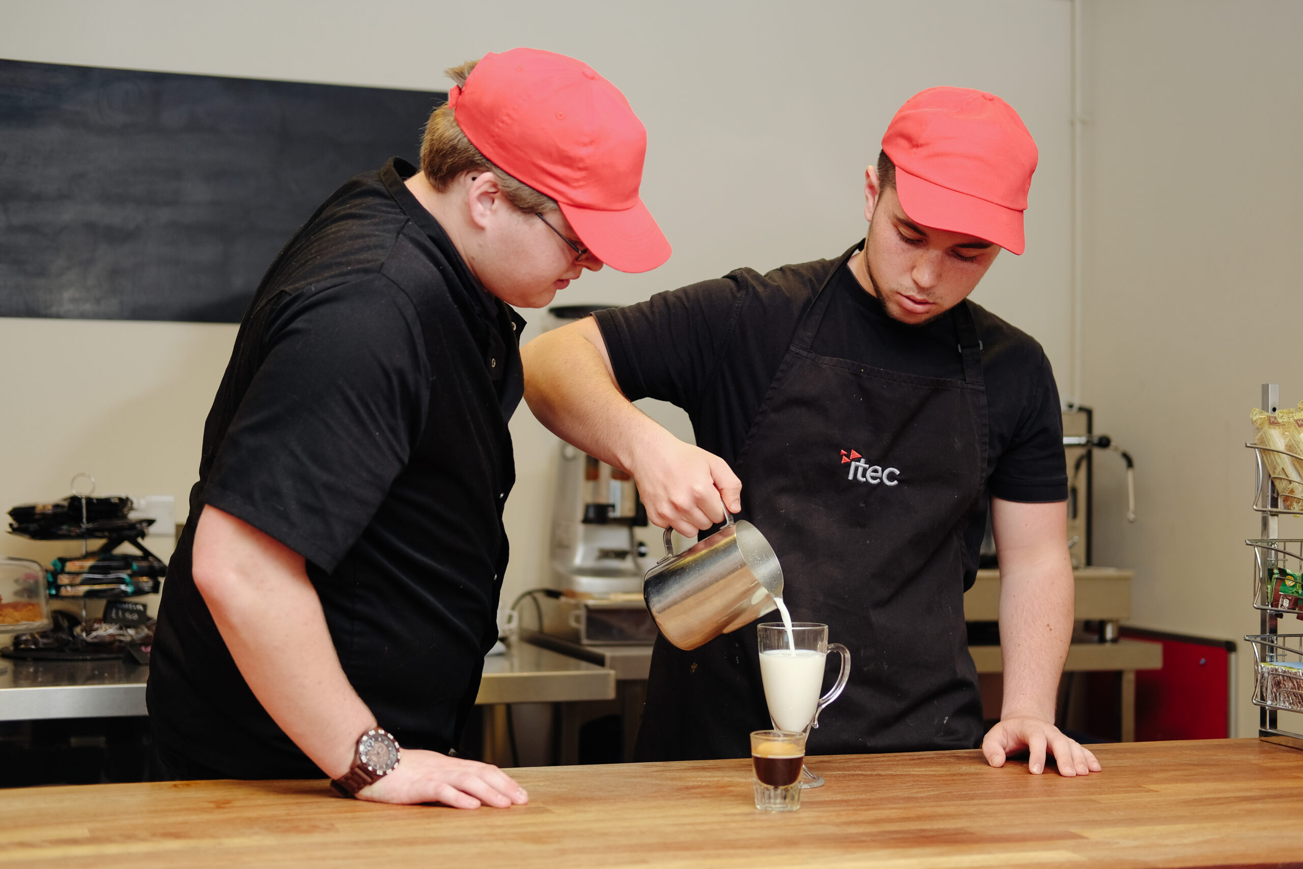 Two Barista learners pouring a coffee