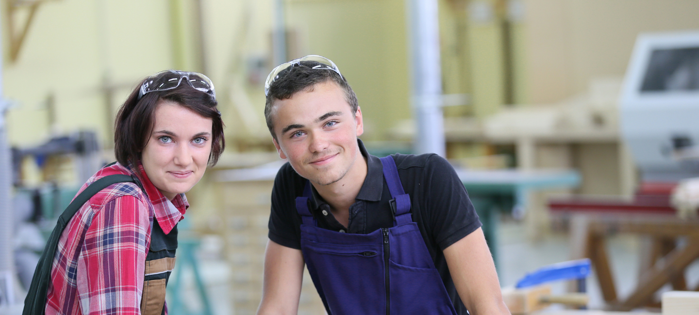 2 woodwork learners smiling at the camera